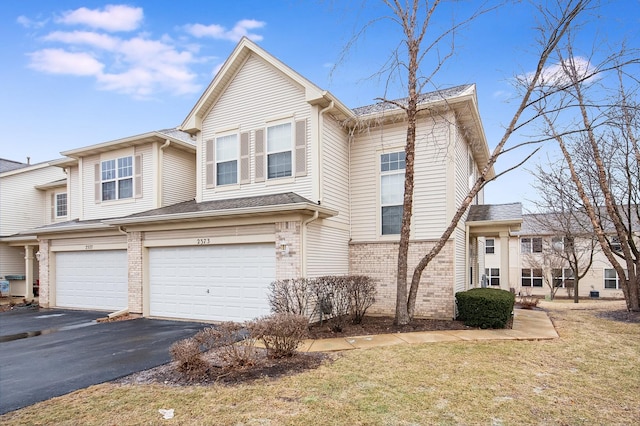 view of front of house featuring a garage, a front yard, aphalt driveway, and brick siding