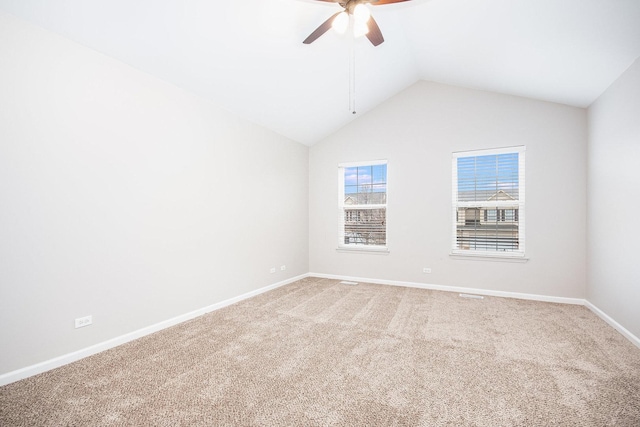 empty room featuring lofted ceiling, ceiling fan, carpet flooring, and baseboards