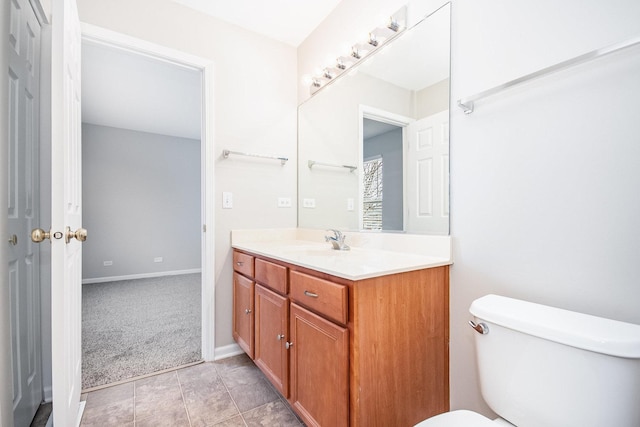 bathroom with toilet, tile patterned floors, baseboards, and vanity