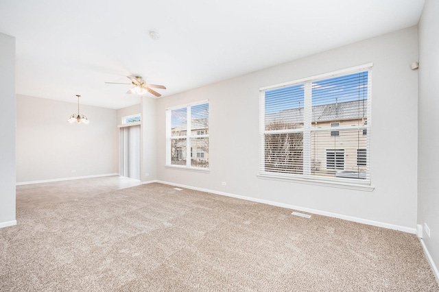 carpeted spare room with baseboards and ceiling fan with notable chandelier