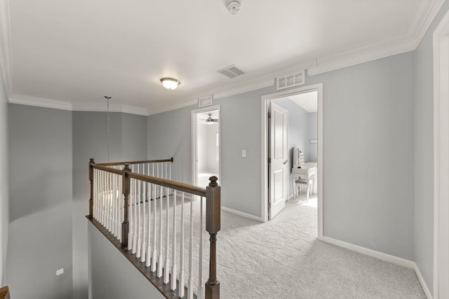 hallway with light carpet, an upstairs landing, visible vents, and baseboards