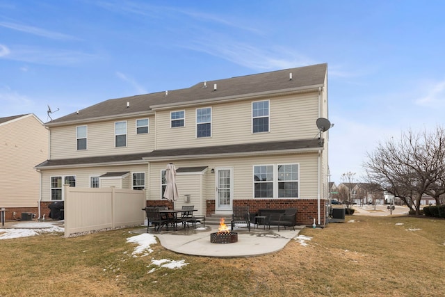 rear view of house with entry steps, a fire pit, brick siding, a lawn, and a patio area