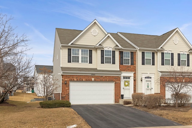 multi unit property with driveway, a garage, and brick siding