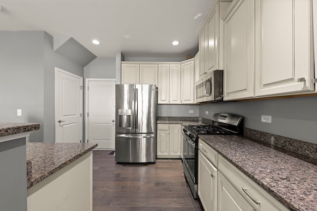 kitchen with dark wood-style flooring, recessed lighting, appliances with stainless steel finishes, white cabinetry, and dark stone countertops