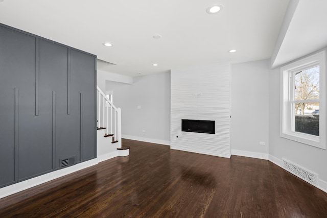 unfurnished living room with visible vents, wood finished floors, stairs, a fireplace, and recessed lighting