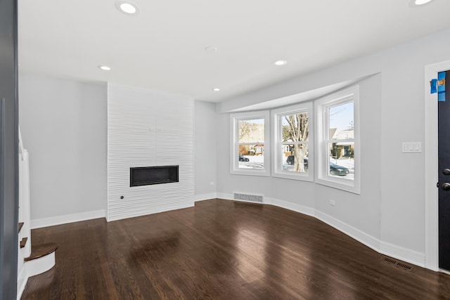 unfurnished living room with a large fireplace, baseboards, visible vents, wood finished floors, and recessed lighting