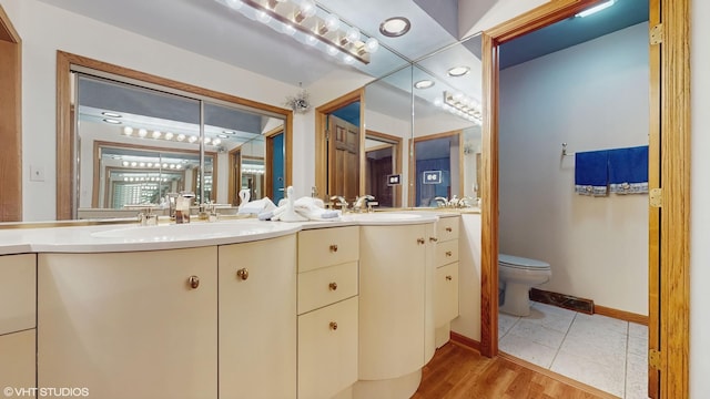 full bathroom featuring double vanity, a sink, toilet, and baseboards