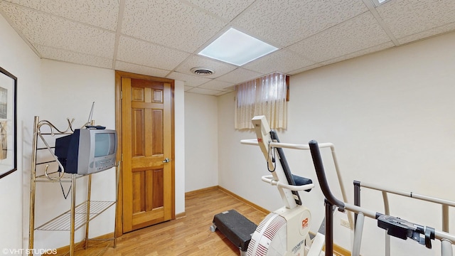 workout area with a drop ceiling, wood finished floors, visible vents, and baseboards