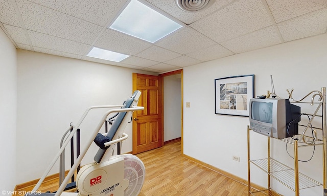 workout room with baseboards, visible vents, light wood-style flooring, and a drop ceiling