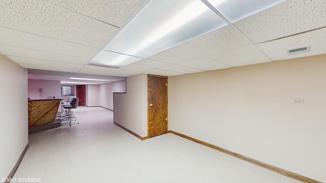 hall featuring a paneled ceiling, tile patterned floors, visible vents, and baseboards