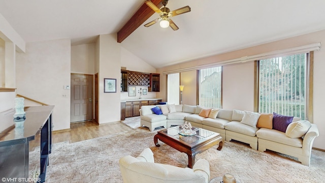 living room with high vaulted ceiling, a ceiling fan, baseboards, light wood-type flooring, and beamed ceiling