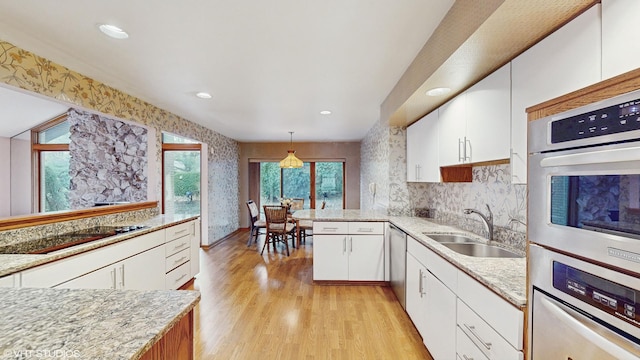 kitchen with stainless steel appliances, light wood-type flooring, a sink, and white cabinets