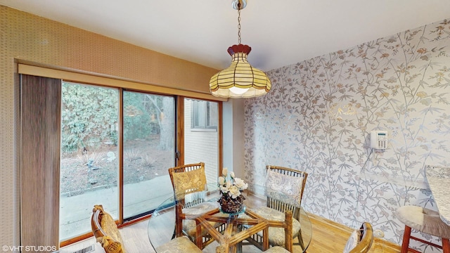 dining space with wood finished floors and wallpapered walls