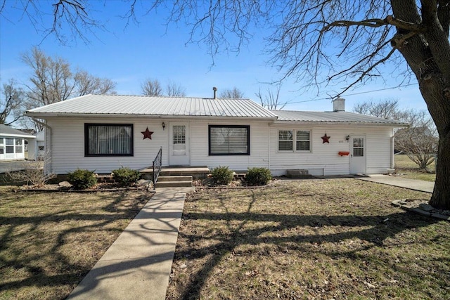 ranch-style house with a chimney, metal roof, and a front lawn