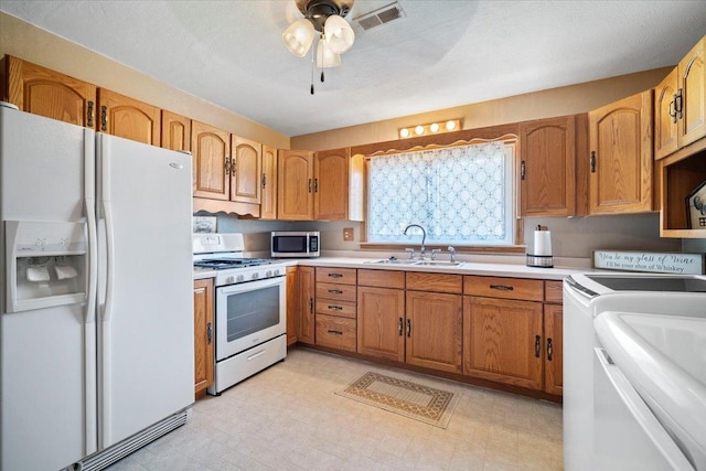 kitchen with visible vents, light floors, white appliances, and a sink