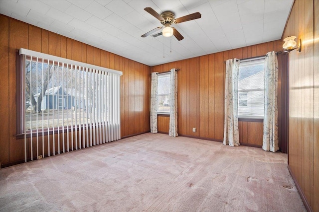 unfurnished room with wood walls, carpet floors, and ceiling fan