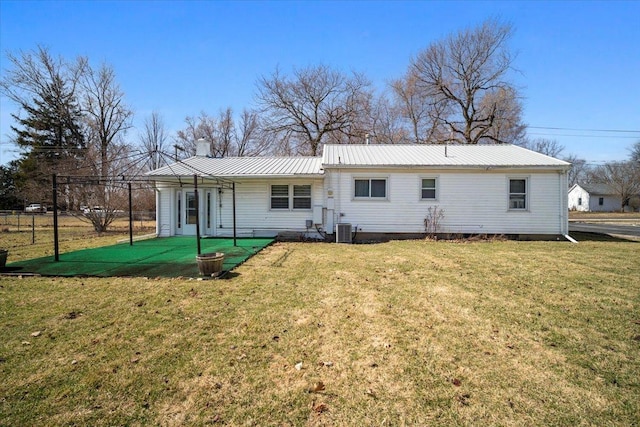 back of property featuring metal roof, a lawn, cooling unit, and a chimney