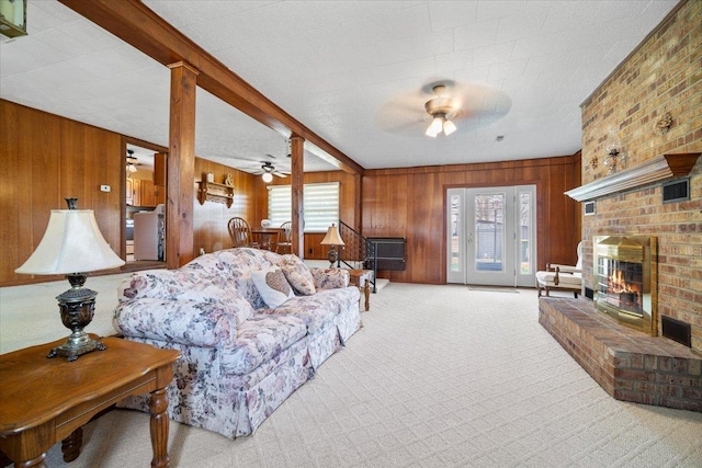 living area with visible vents, a fireplace, ceiling fan, wood walls, and carpet flooring