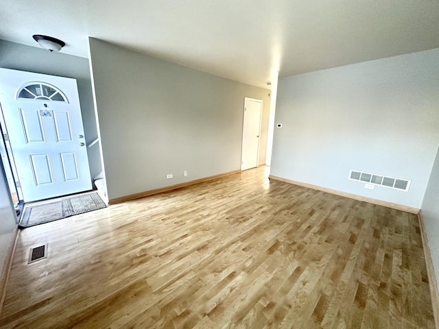 foyer entrance with visible vents, light wood-style flooring, and baseboards