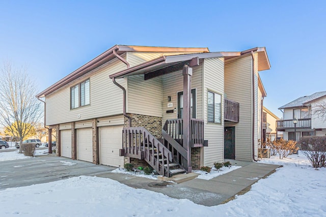 view of front of home featuring an attached garage, driveway, stairs, and brick siding