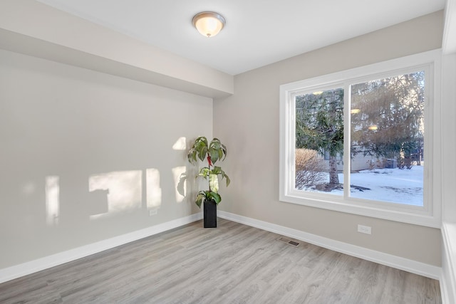 empty room featuring light wood finished floors, visible vents, and baseboards