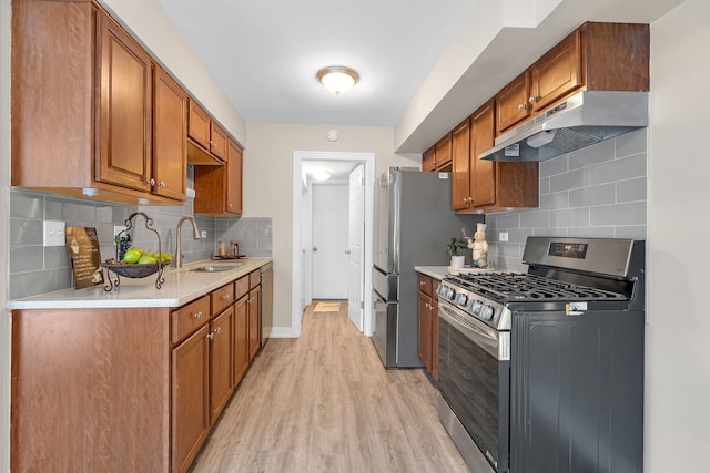 kitchen featuring under cabinet range hood, stainless steel appliances, a sink, light countertops, and brown cabinetry