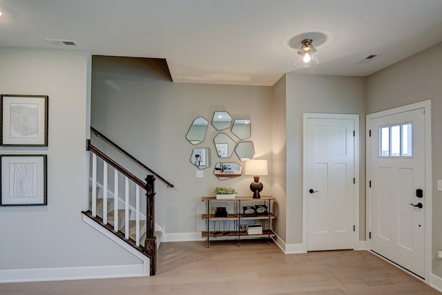 entrance foyer with baseboards, stairway, visible vents, and light wood-style floors