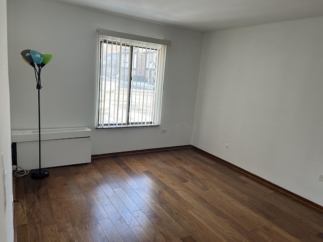 unfurnished room with dark wood-type flooring and baseboards