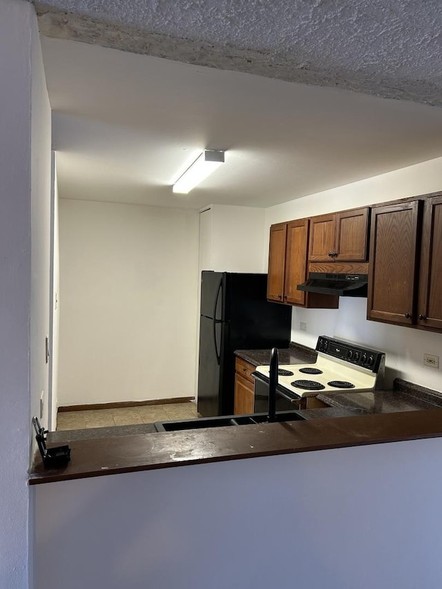 kitchen featuring dark countertops, electric range, under cabinet range hood, and a textured ceiling