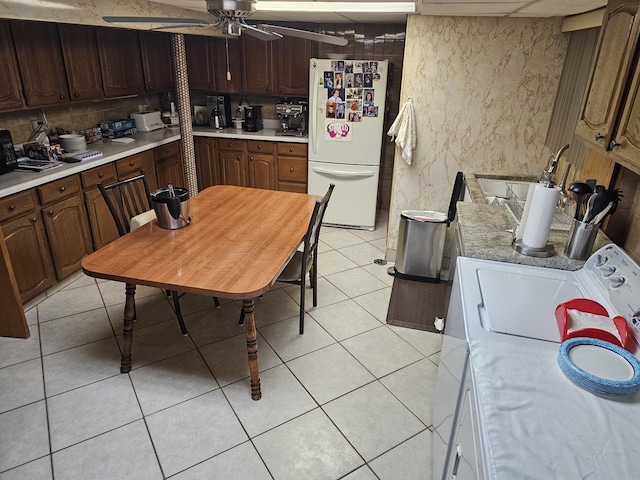 kitchen with light tile patterned flooring, light countertops, freestanding refrigerator, and tasteful backsplash