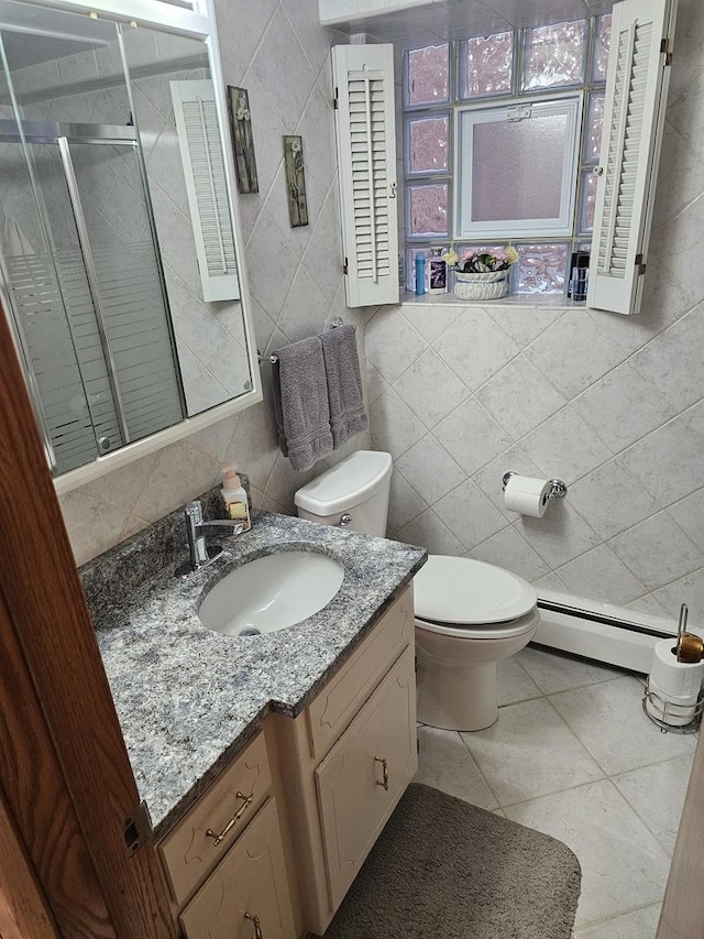 bathroom with a baseboard heating unit, toilet, vanity, a stall shower, and tile walls