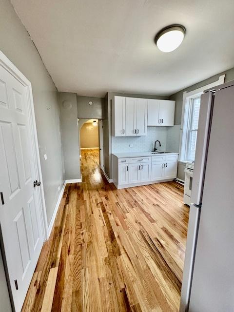 kitchen with light wood-style floors, white cabinetry, light countertops, and freestanding refrigerator