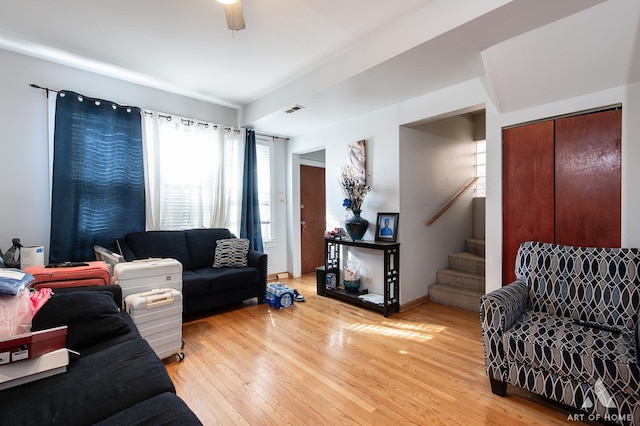 living room with stairs, visible vents, and light wood-style floors