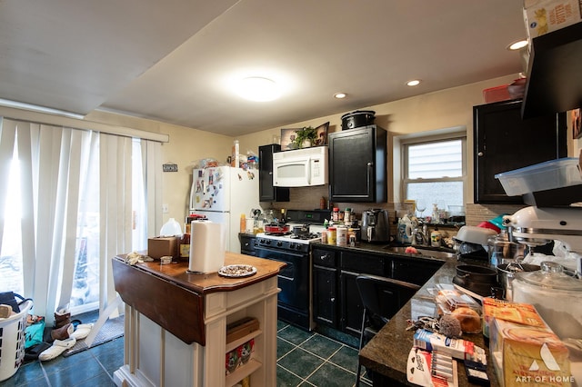 kitchen with dark tile patterned flooring, white appliances, a sink, dark cabinetry, and tasteful backsplash