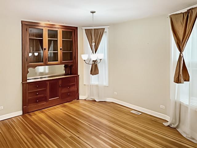 unfurnished dining area with visible vents, light wood-style flooring, and baseboards