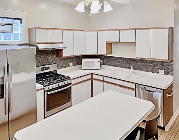 kitchen with stainless steel appliances, a sink, white cabinetry, and under cabinet range hood