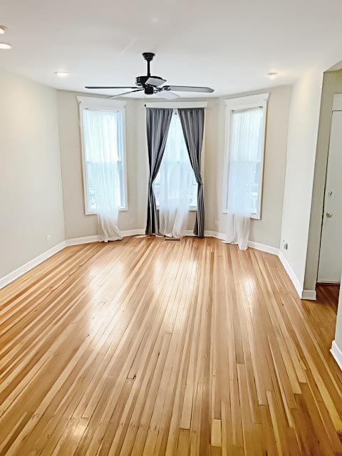 unfurnished room featuring ceiling fan, light wood-style flooring, and baseboards