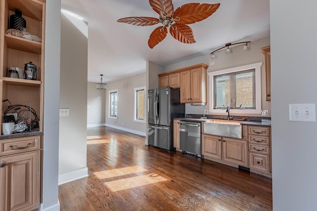 kitchen with dark countertops, appliances with stainless steel finishes, dark wood-type flooring, and a sink