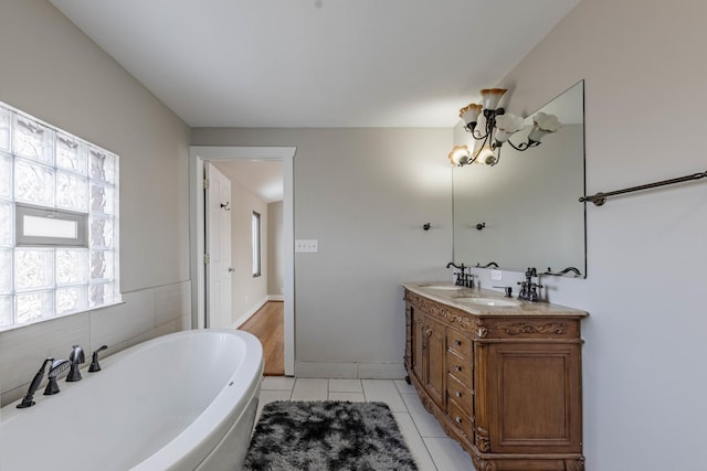 full bathroom featuring a sink, double vanity, a freestanding tub, and tile patterned floors