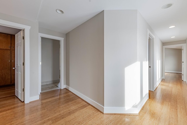 hallway with light wood-type flooring and baseboards