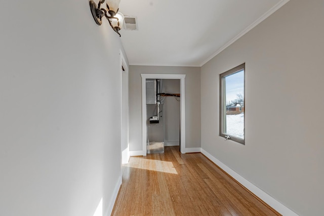 unfurnished bedroom with light wood-style flooring, visible vents, baseboards, a closet, and crown molding