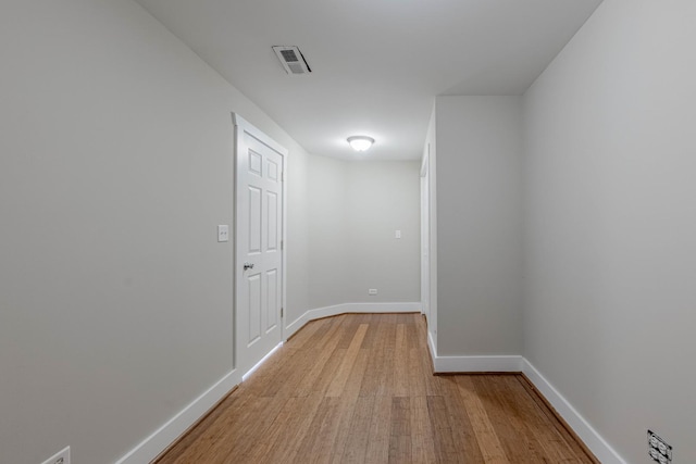 hall featuring light wood finished floors, visible vents, and baseboards