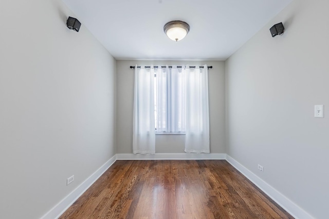 spare room featuring dark wood-type flooring and baseboards