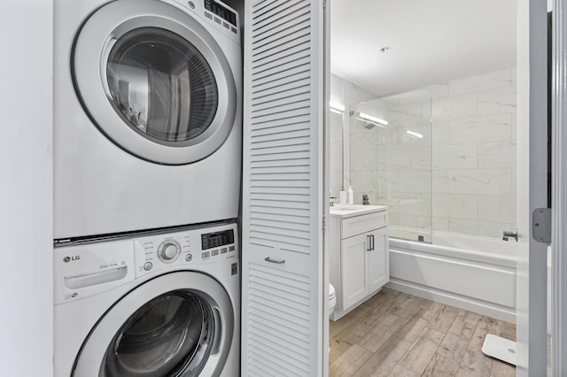 laundry area with light wood-type flooring, stacked washing maching and dryer, and laundry area