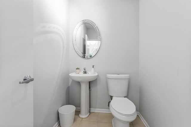 bathroom with tile patterned flooring, baseboards, and toilet