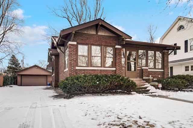 view of front of house with brick siding, a detached garage, and an outdoor structure