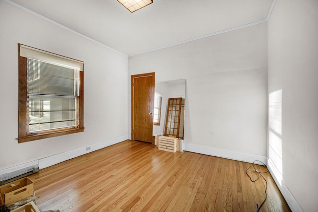 unfurnished room featuring ornamental molding, light wood finished floors, a wealth of natural light, and baseboards