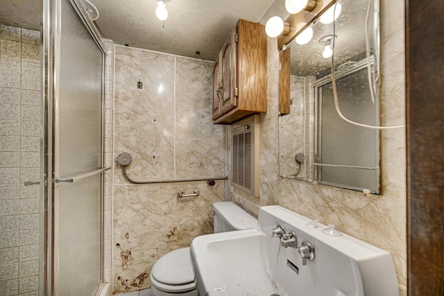 bathroom with toilet, a shower with door, a textured ceiling, and tile walls