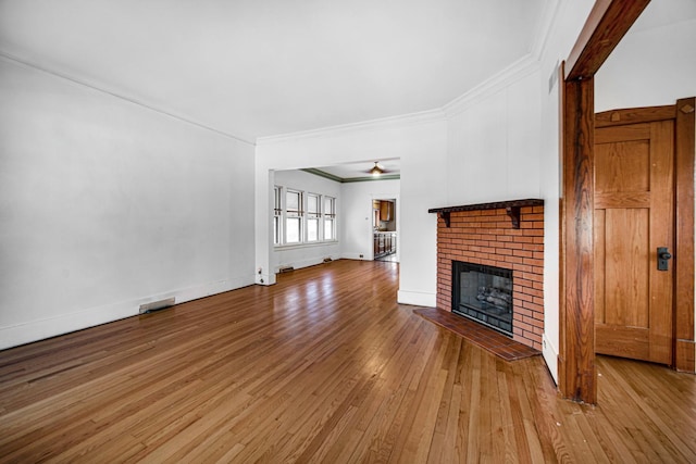 unfurnished living room featuring baseboards, ornamental molding, a fireplace, and light wood-style floors