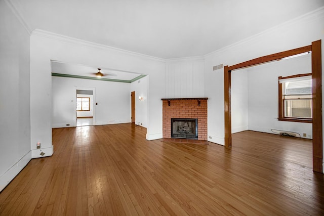 unfurnished living room featuring visible vents, ceiling fan, ornamental molding, wood finished floors, and a fireplace